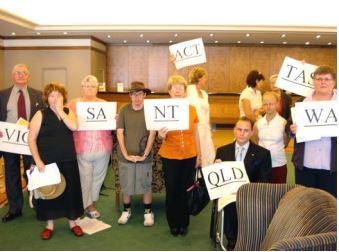 A group of family members holding signs. The signs read VIC, SA, NT, ACT, TAS, QLD, WA.