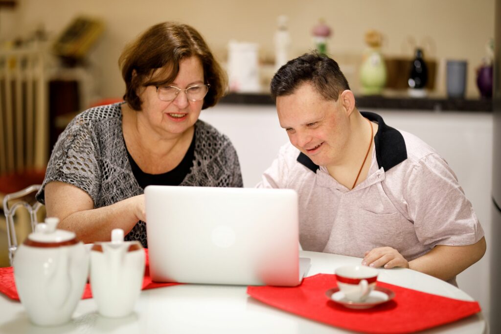 A woman and a man sitting at a table and looking at a laptop together